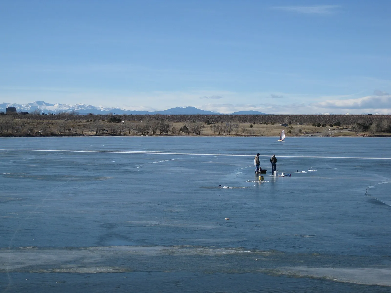 Frozen Cherry Creek Reservoir in winter with ice anglers out on the ice and the Front Range mountains on the horizon